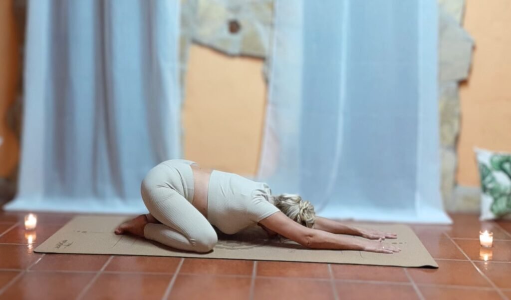 Marya Vázquez vestida en tonos suaves, practicando balasana o la postura del niño en la clase de yin yoga Althaia