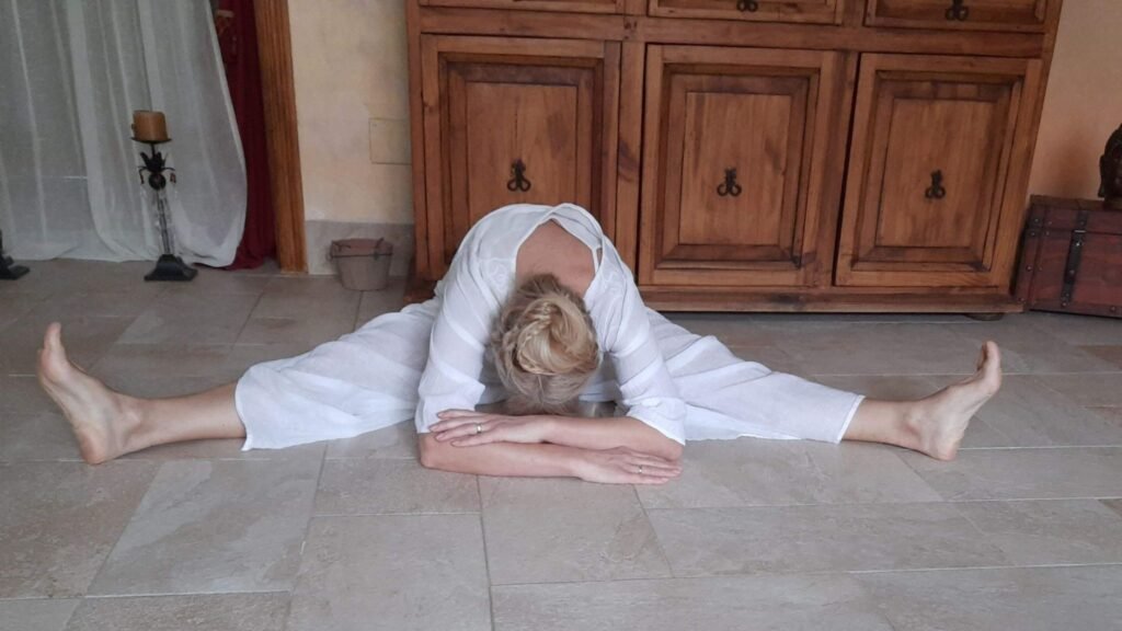 Marya Vázquez vestida de blanco en la postura de la libélula en la clase de yin yoga